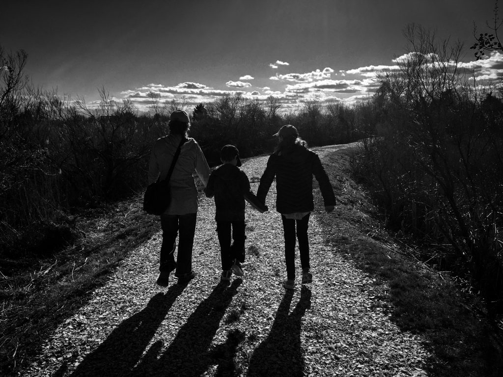 silhouettes of mother and 2 children holding hands hiking