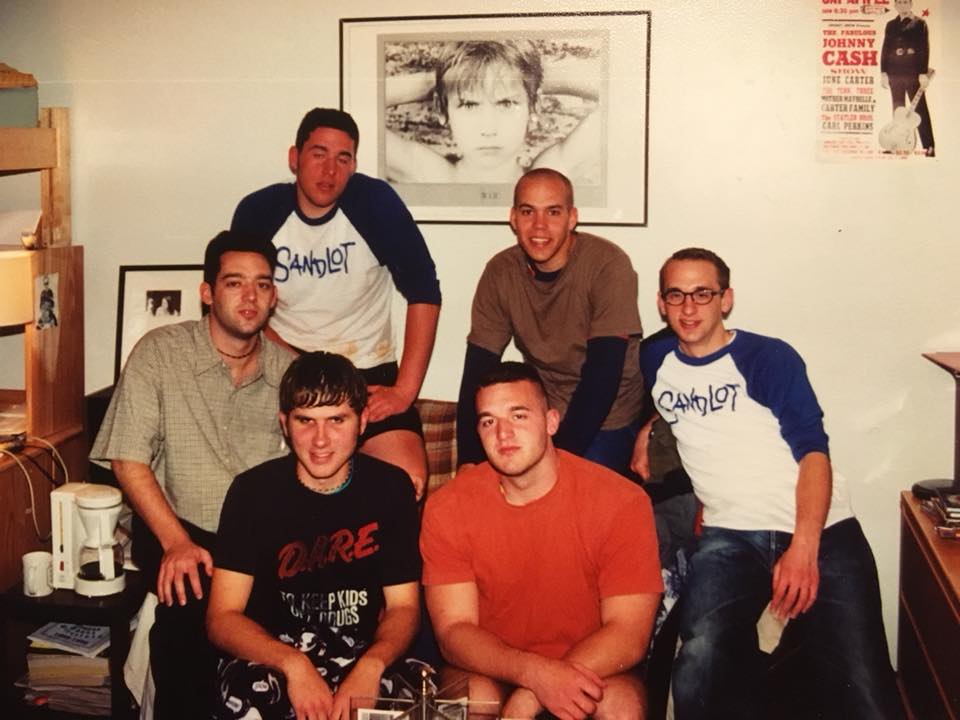 group of young men posing for a pic in a college dorm room 