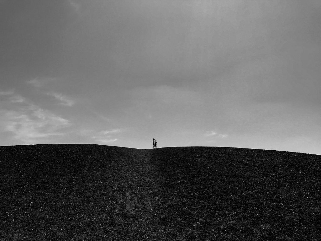 2 shadowed figures on black hill in black & white